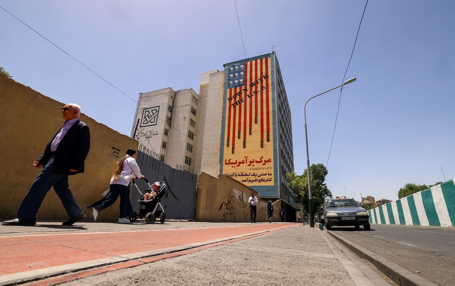People walk near anti-US mural with the slogan "Down with the USA" and skulls replacing the stars on the flag, in Tehran, on May 20, 2025. Photo: Atta Kenare/AFP